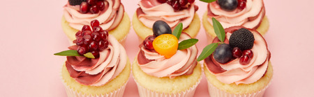 Panoramic shot of sweet cupcakes with berries and fruits on pink surfaceの写真素材