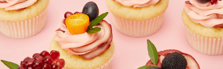 Panoramic shot of sweet cupcakes with berries and fruits on pink surfaceの写真素材