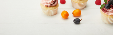 Panoramic shot of cupcakes with fruits and berries on white surfaceの写真素材