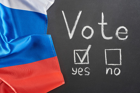 Top view of vote lettering and check mark near yes word on black chalkboard near flag of Russiaの写真素材