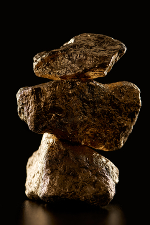 Close up of gold textured shiny stones in pile isolated on black backgroundの写真素材