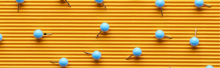 Panoramic shot of push pins on textured yellow paperの写真素材
