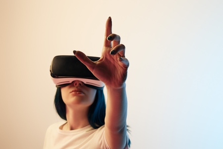 Selective focus of brunette girl wearing virtual reality headset and gesturing on beige and blue...