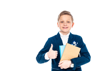 smiling schoolboy showing thumb up sign and holding books Isolated On White