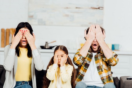 shocked family covering face while watching tv at homeの写真素材
