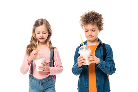 Two schoolkids with backpacks holding milkshakes isolated on white backgroundの写真素材