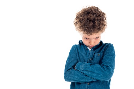Sad curly kid in denim shirt standing with crossed arms isolated on white background