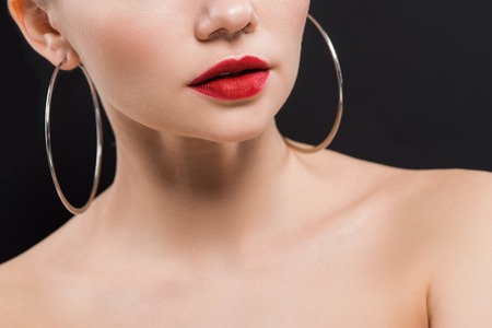 cropped view of naked young woman in earrings isolated on blackの写真素材