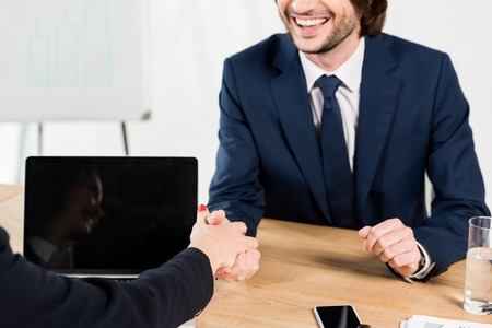 cropped view of cheerful man shaking hands with recruiter in officeの写真素材