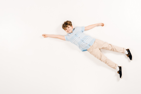 happy child looking at camera and gesturing while lying on whiteの写真素材