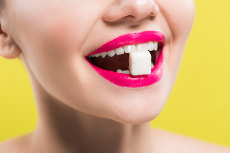 cropped view of happy woman eating sugar cube isolated on yellowの写真素材