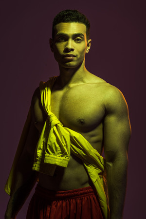 handsome mixed red man with muscular torso looking at camera on dark backgroundの写真素材