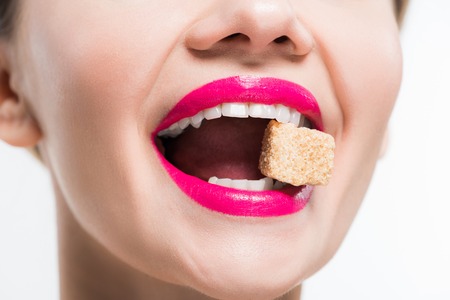 cropped view of happy woman eating sugar cube isolated on whiteの写真素材