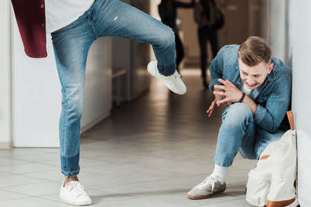 cropped view of two students fighting in corridor in college