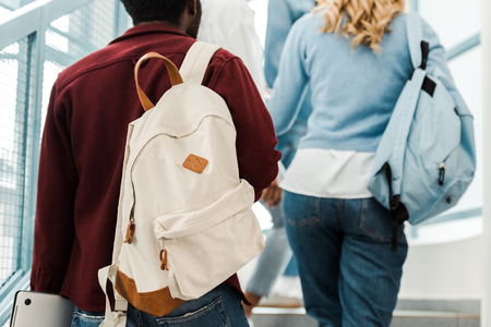 cropped view of students with backpacks on stairs in university
