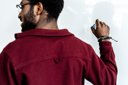 cropped view of african american student in glasses writing on flipchartの写真素材