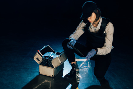 investigator in uniform putting evidence in zipper storage bags at crime scene