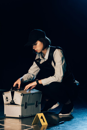 investigator in cap opening investigation kit at crime sceneの写真素材