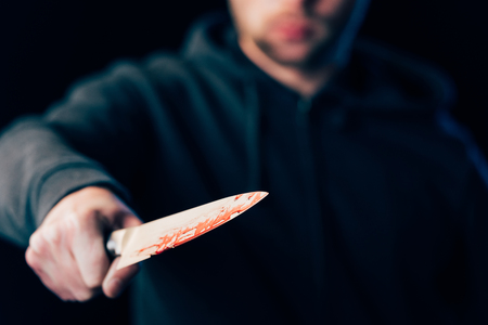 selective focus of killer holding knife isolated on blackの写真素材