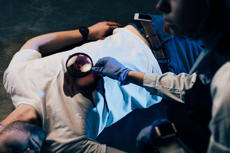 partial view of investigator using magnifying glass at crime sceneの写真素材