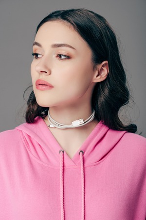 beautiful young woman with usb cable around neck looking away isolated on greyの写真素材