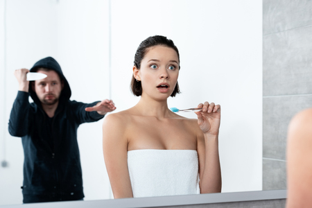 killer attacking woman with knife while she brushing teeth in bathroomの写真素材