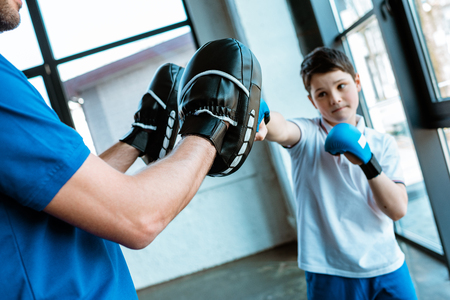 Boy in boxing gloves working out with coach at gymの写真素材