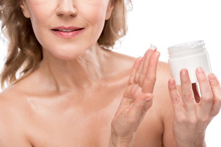 Cropped view of mature woman with perfect skin holding container with cosmetic cream isolated on white backgroundの写真素材