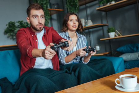 Selective focus of handsome man and brunette woman playing video game in living roomの写真素材