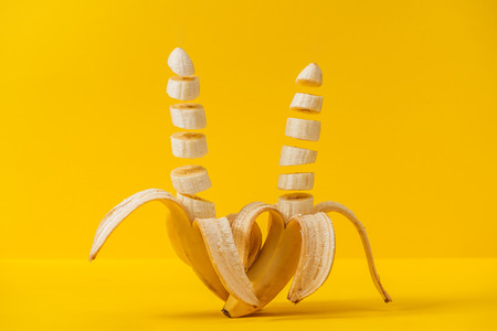 Tropical fresh sliced delicious bananas isolated on yellow backgroundの写真素材