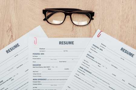 Top view of print resume templates and glasses on wooden tableの写真素材
