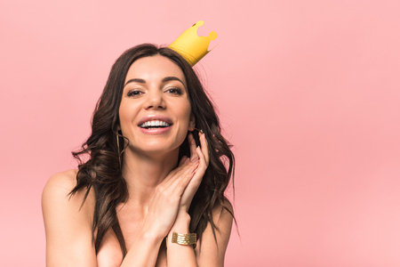 Attractive girl in crown smiling isolated on pink backgroundの写真素材