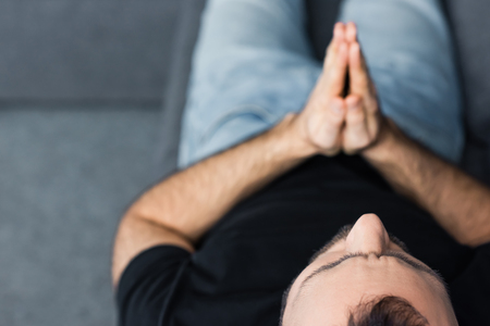 Overhead view of lonely man praying while sitting at homeの写真素材