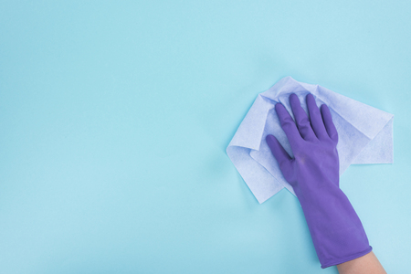 Cropped view of cleaner in purple rubber glove holding rag on blue backgroundの写真素材