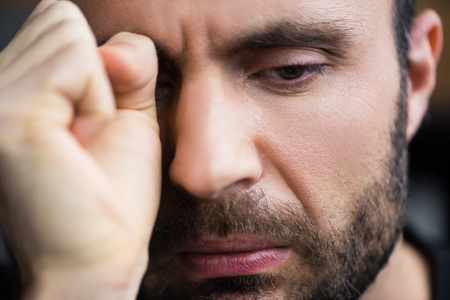 Portrait of handsome crying man wiping tears away with handの写真素材