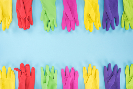 Top view of multicolored bright rubber gloves on blue background with copy space