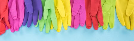 Panoramic shot of bright multicolored rubber gloves on blue backgroundの写真素材