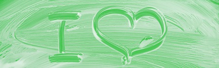 Panoramic shot of glass covered with white foam on green background with I letter and heart signの写真素材
