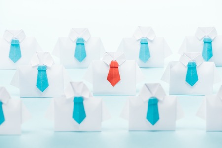 Origami white shirts with blue ties with one red on blue background, think different concept