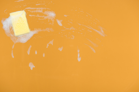 Yellow sponge with foam on orange backgroundの写真素材