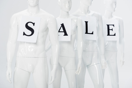 papers with sale lettering on white plastic mannequins isolated on greyの写真素材