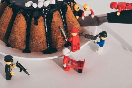 KYIV, UKRAINE - MARCH 15, 2019: plastic lego minifigures cutting delicious cake with knife