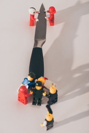 KYIV, UKRAINE - MARCH 15, 2019: close up view of plastic lego figurines carrying metal knife on whiteのeditorial素材