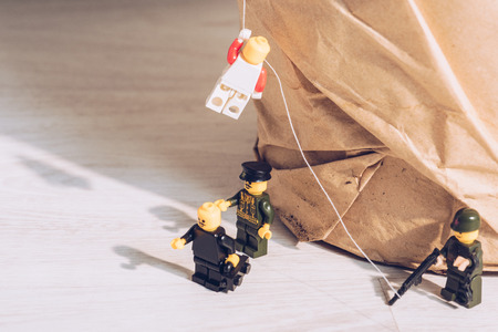 KYIV, UKRAINE - MARCH 15, 2019: toy policemen standing with weapon while plastic lego figurine climbing ropeのeditorial素材