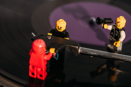 KYIV, UKRAINE - MARCH 15, 2019: close up view of plastic lego figurines fixing vinyl record player