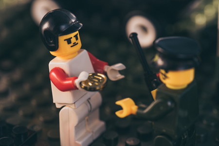 KYIV, UKRAINE - MARCH 15, 2019: Selective Focus of lego driver figure in hat bribing policeman figurine with golden coinのeditorial素材