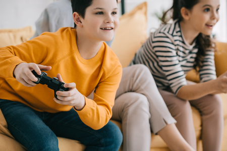 selective focus of cheerful boy playing video game together with sisterの写真素材