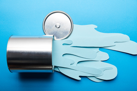 top view of spilled paper cut blue paint near silver shiny can and capの写真素材