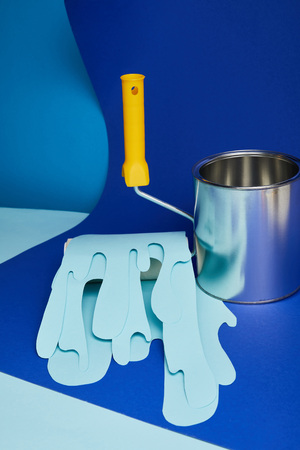 metal shiny can near roller with dripping paper cut paint on bright blue backgroundの写真素材