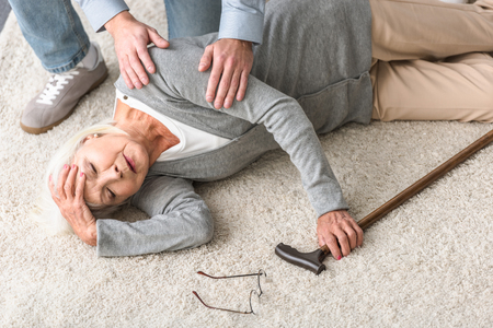 cropped view of man helping senior mother with heart attack fallen on carpetの写真素材